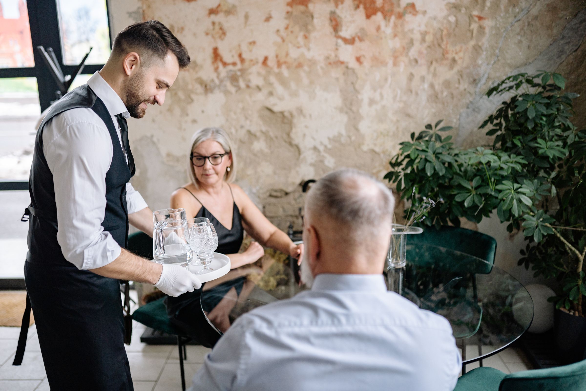 A waiter serving drinks to seated guests in a restaurant