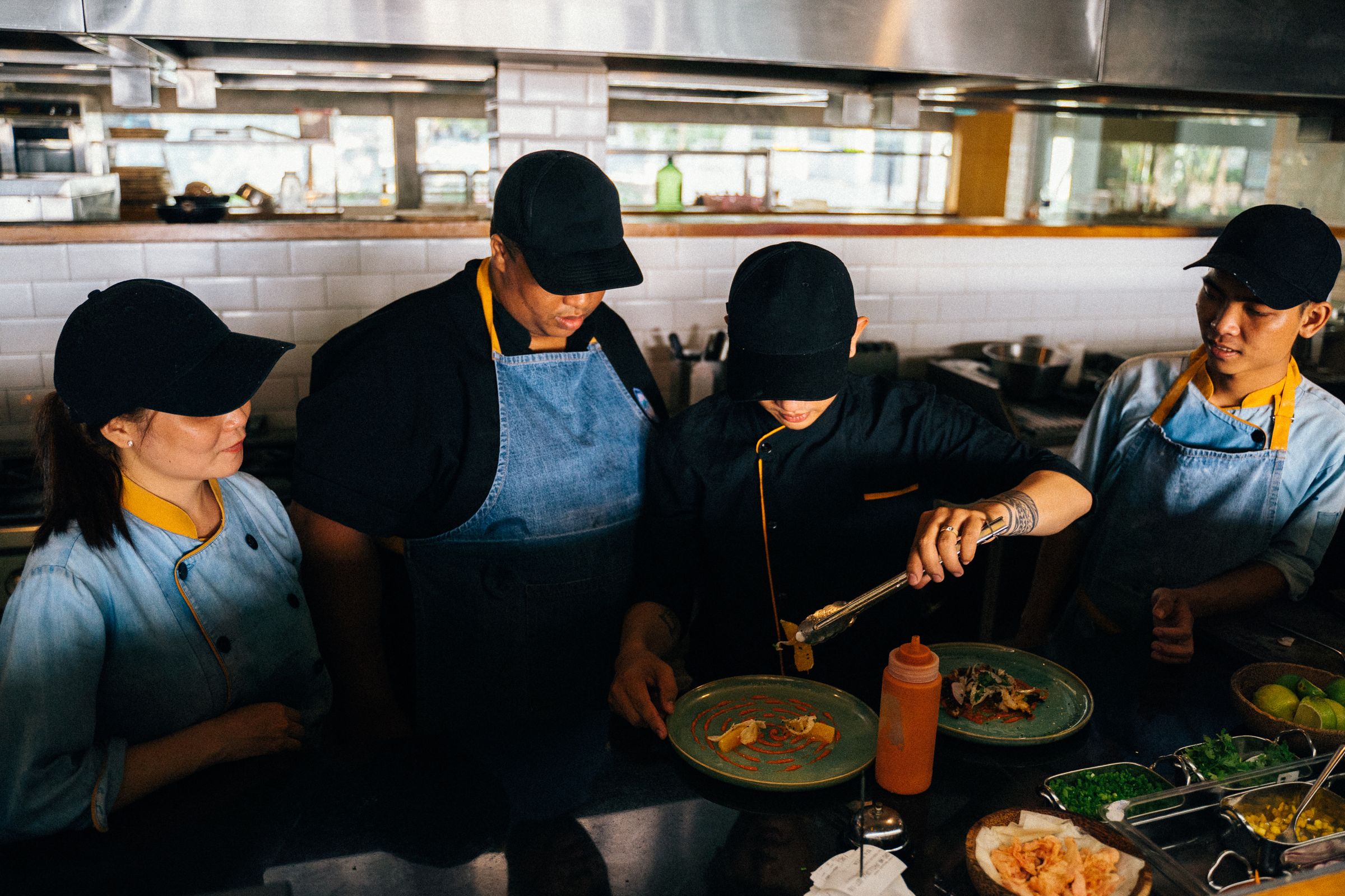 A kitchen team working side by side over the pass